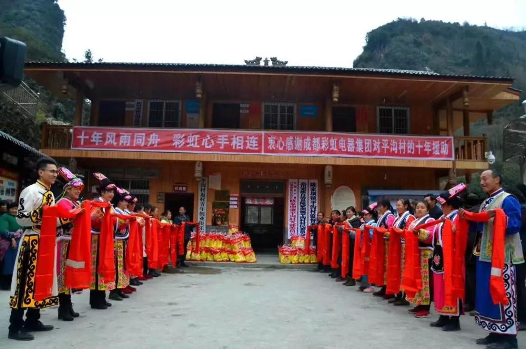 怀感恩之心，平沟村村民手持羌红在爱游戏（中国）公司援建的平沟村便民服务楼前热情等待爱游戏（中国）亲人们的到来
